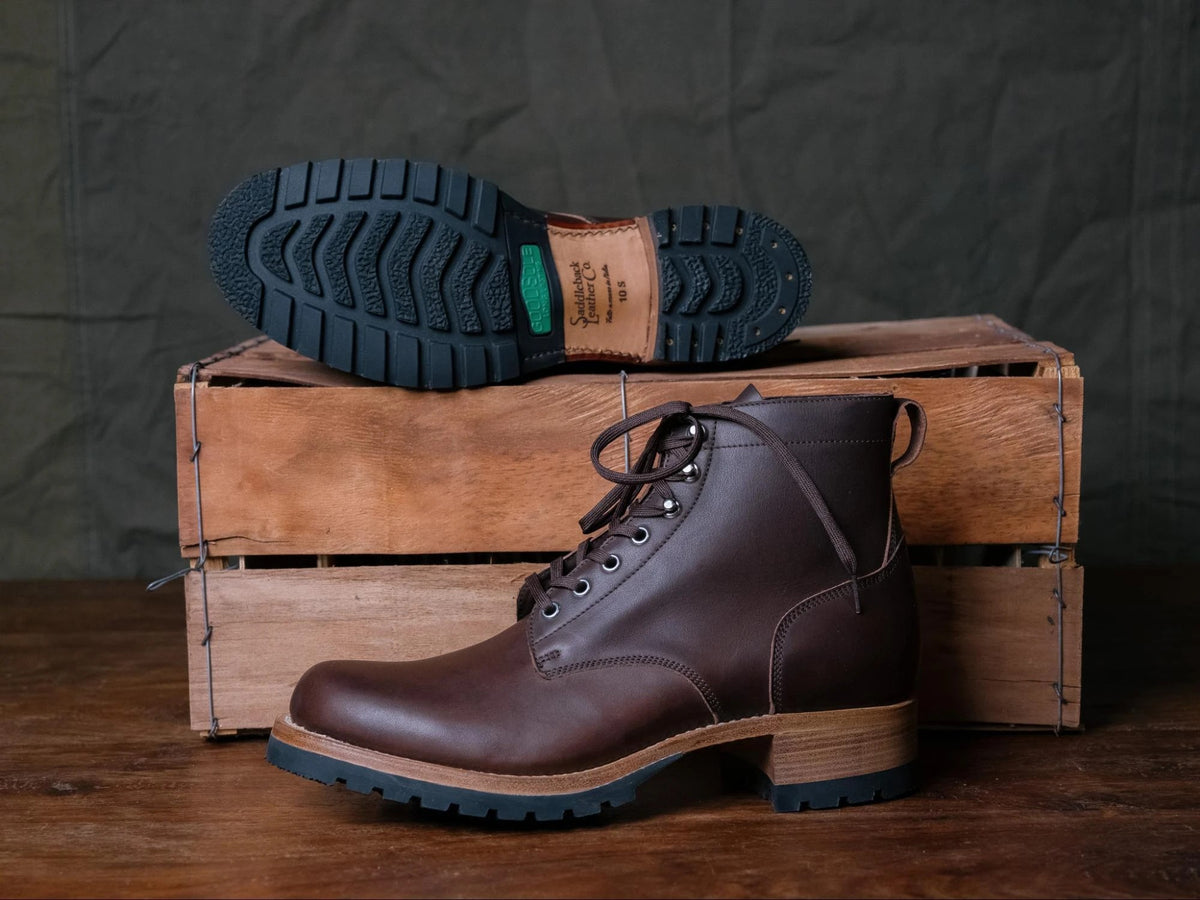 Huntsman Boots - Dark Coffee Brown, one standing and one on a crate showing the lugged rubber outsole