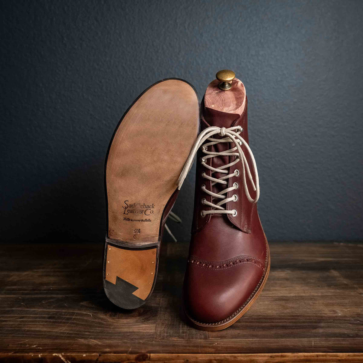 Officer Boot in Oxblood, one boot standing with cream laces beside one showing its leather sole