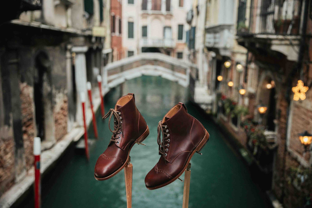 Officer's Boot in Oxblood, pair on wooden stands above a Venice canal
