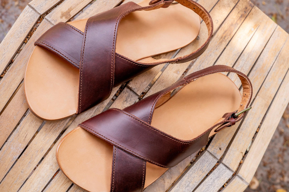 Jesus Sandals in Chestnut, top view of a pair with crisscross straps on a weathered wooden bench