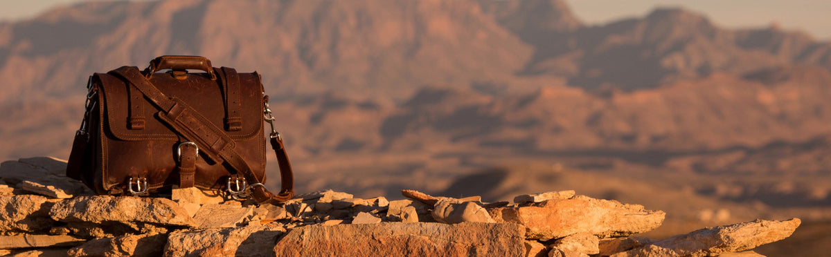 Large Classic Leather Briefcase in brown on desert rocks with mountains behind at sunset