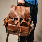 Large Travel Backpack in Burnt Sausage, held by the top handle by a hand