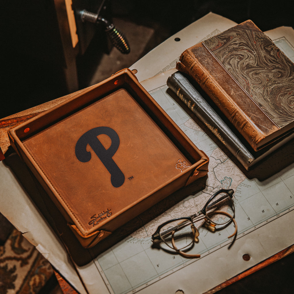 Philadelphia Phillies Leather Valet Tray in Tobacco on a map beside old books and wire-rim glasses