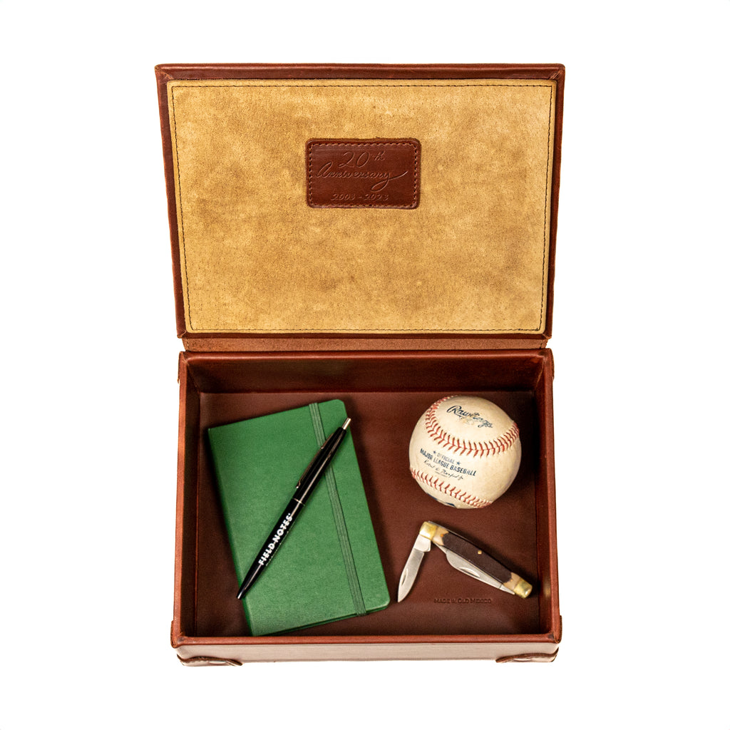 Leather Desk Box in Chestnut, open top-down view with a green notebook, pen, baseball and pocketknife inside