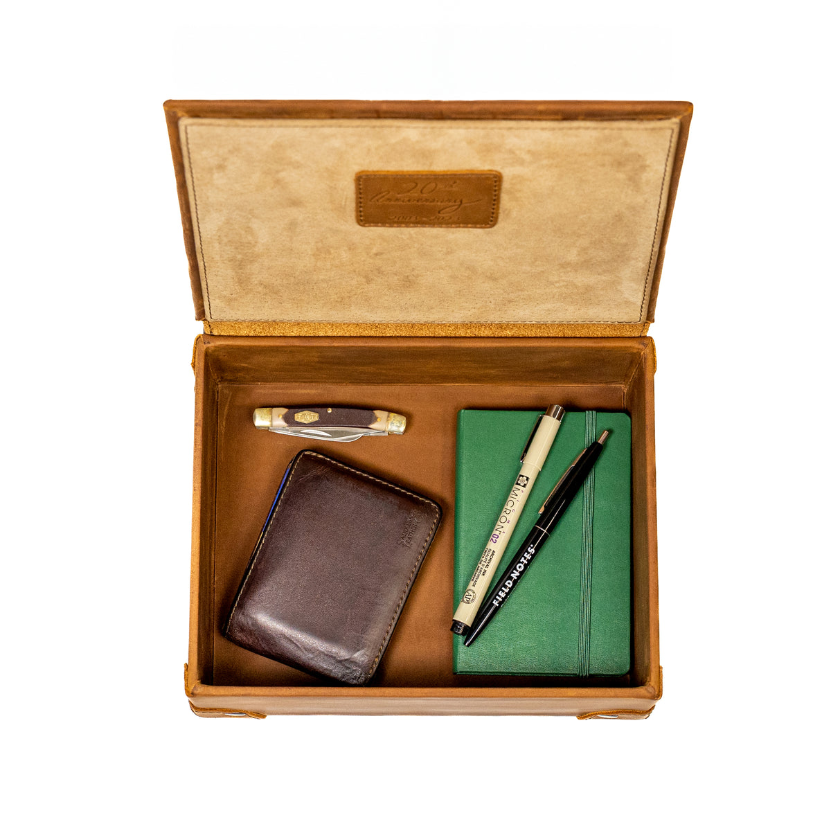 Leather Desk Box in Tobacco, open top-down view with a wallet, pocketknife, pens and green notebook inside