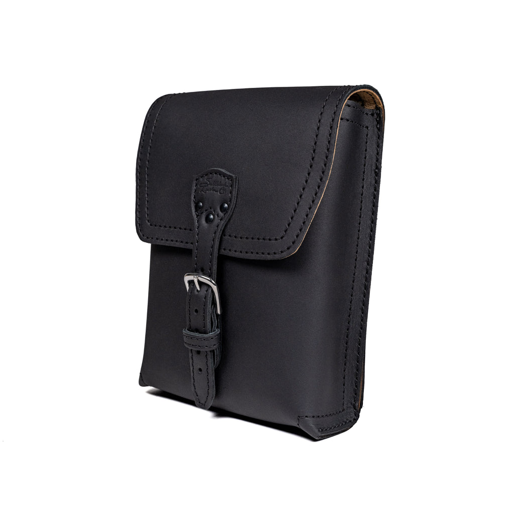 Leather Travel Satchel in Black, angled front view with buckled strap closure on the flap