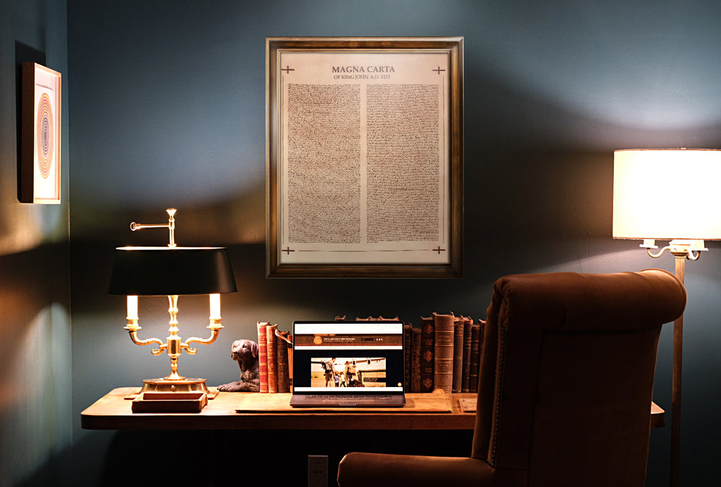 Leather Magna Carta - Natural in a wood frame on a home office wall above a desk with lamp, books and laptop