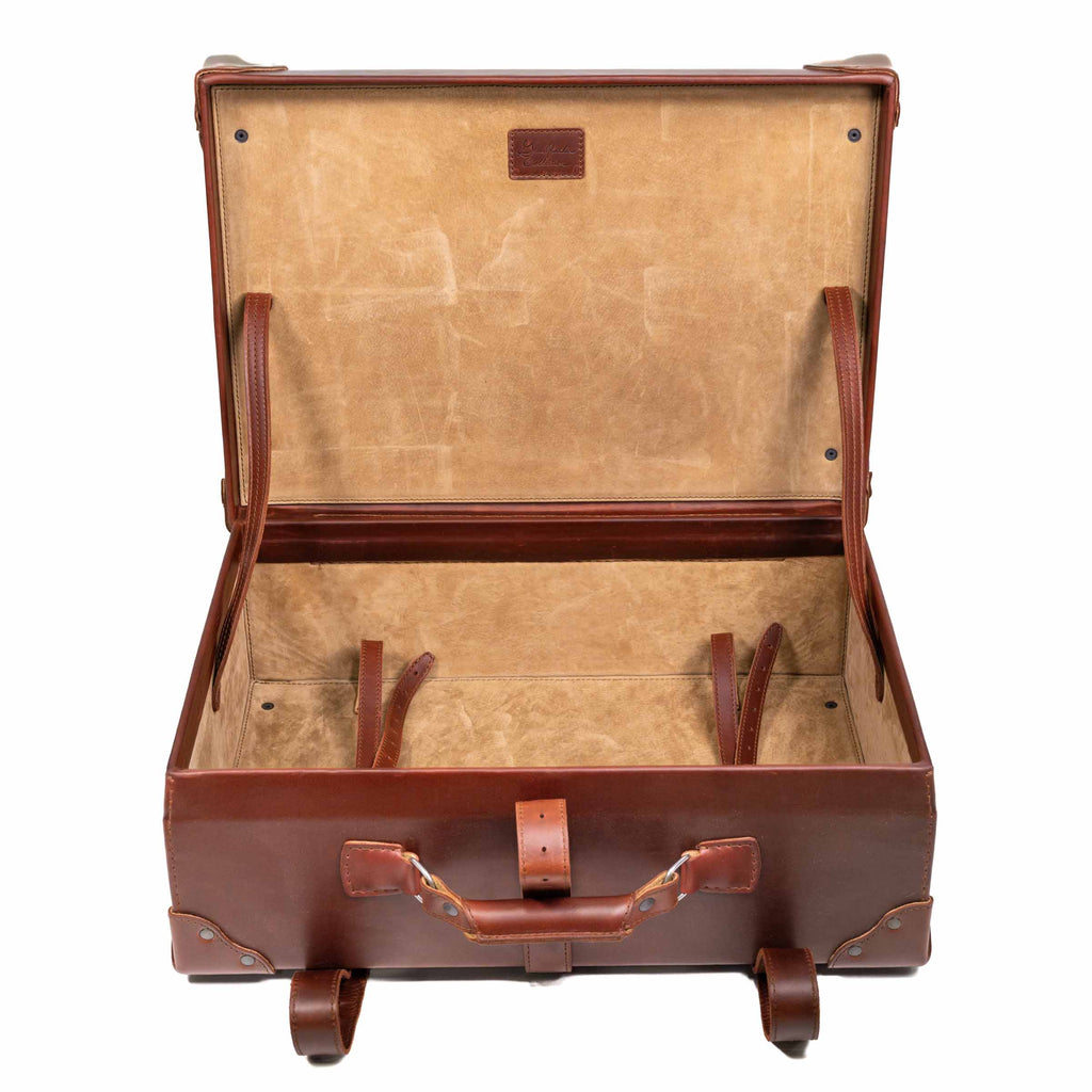 Grandfather Medium Suitcase in Chestnut, opened to show the canvas lining and leather tie-down straps