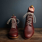 Officer Boot in Oxblood, pair with cream laces and shoe trees on a wooden table
