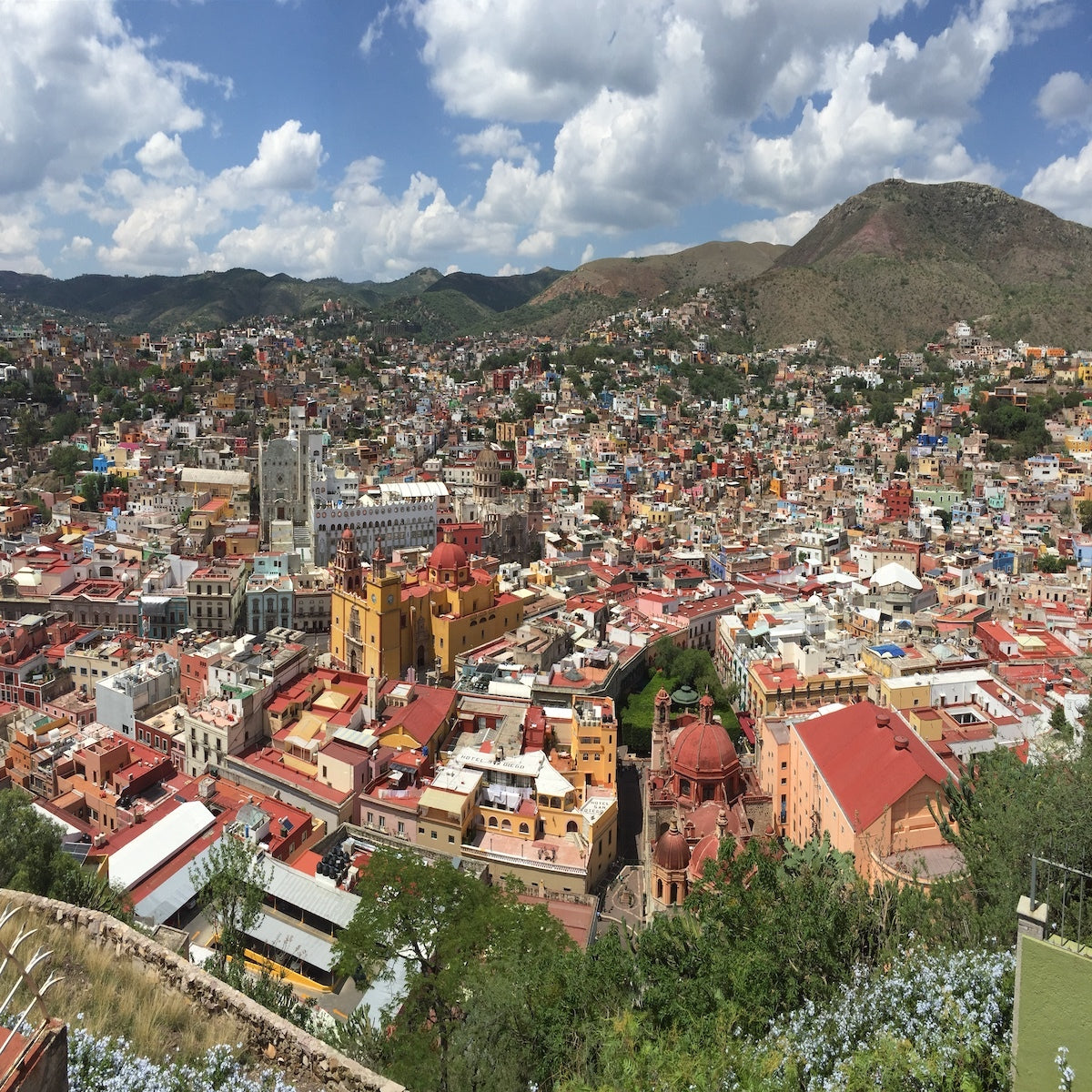 Aerial view of a Mexican hillside town, its houses painted in reds, yellows and blues.