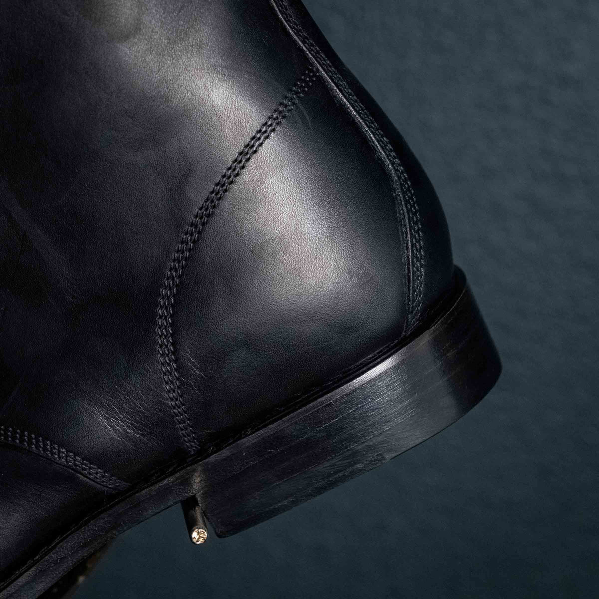 Officer's Boot in Raven Black, close-up of the heel counter stitching and stacked heel