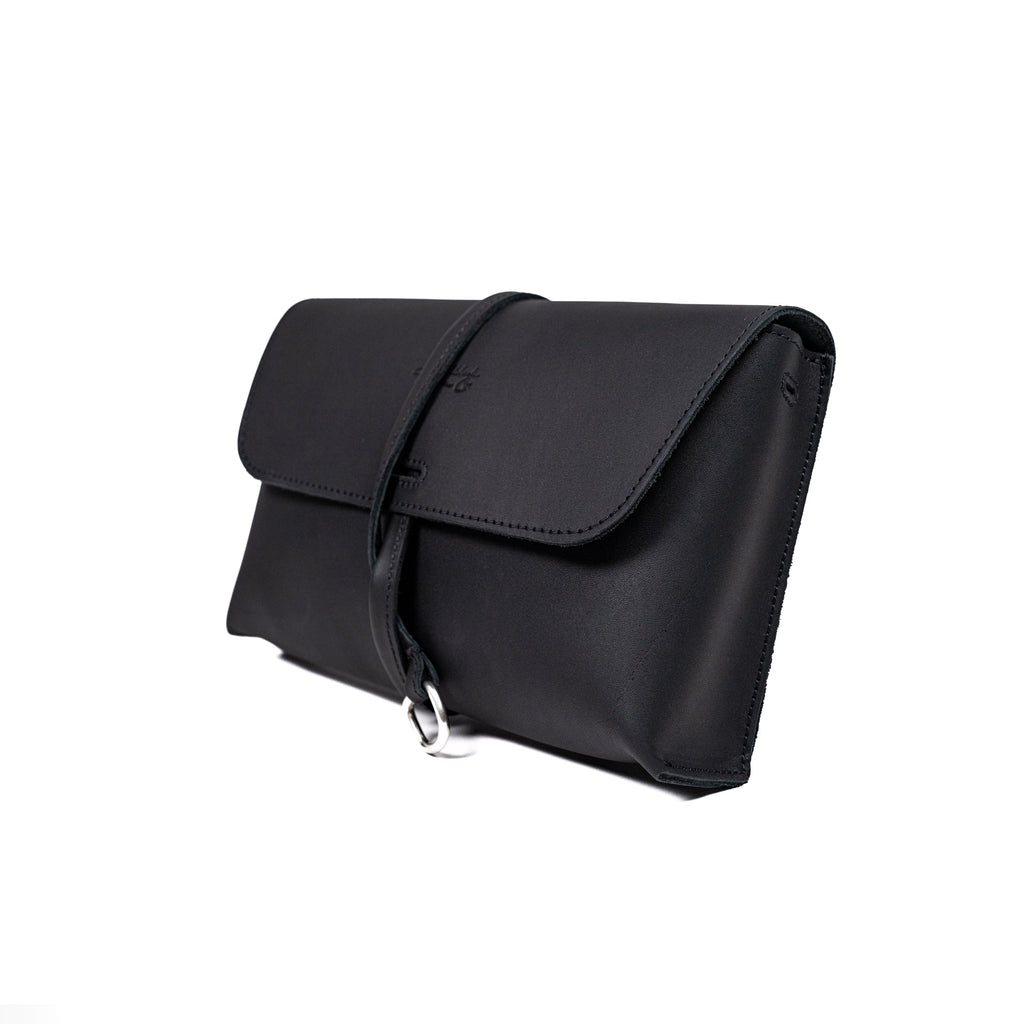 Large Leather Organizer Bag in Black, closed flap with wrapped leather tie and ring, angled view