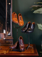 Toe Cap Shoes collection, tan, Raven Black and brown pairs displayed on metal stands by a mirror