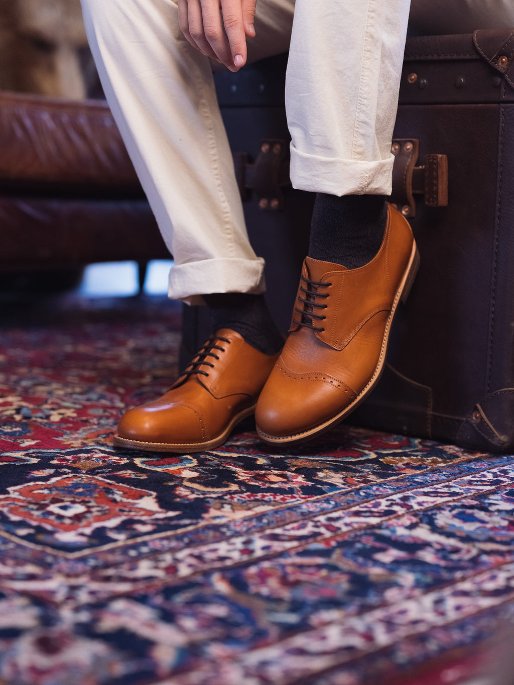 Toe Cap Shoes in English Tan, worn with cuffed cream trousers on a patterned rug