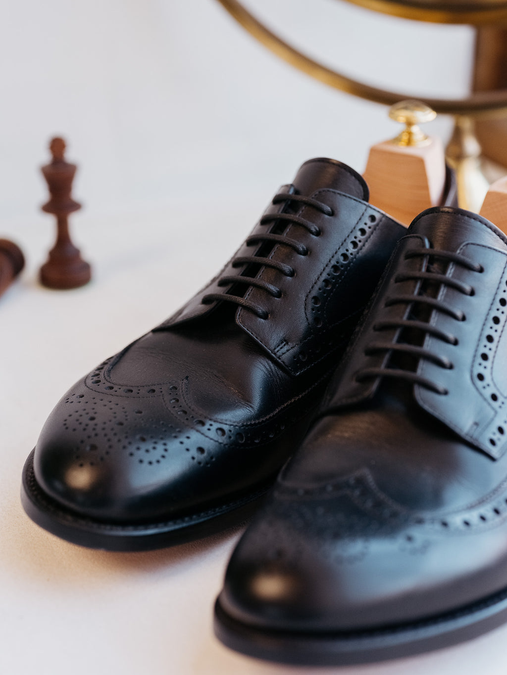 Wingtip Shoes in Raven Black, front close-up of the pair with brogue toes and chess pieces