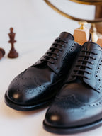 Wingtip Shoes in Raven Black, front close-up of the pair with brogue toes and chess pieces