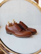 Wingtip Shoes in Chestnut, pair with shoe trees reflected in a round brass mirror
