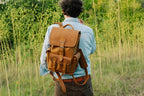 Small Front Pocket Backpack in Tobacco on the back of a man standing in a field of tall green grass