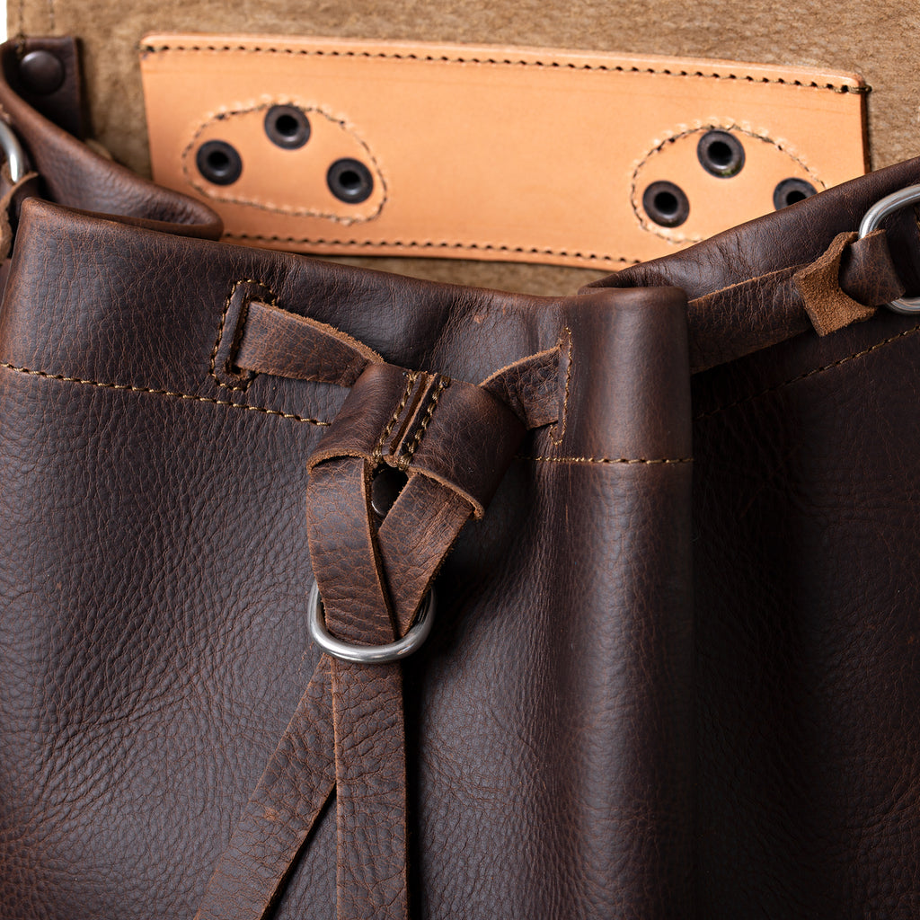 12" Drawstring Backpack in Dark Coffee Brown, close-up of drawstring tie and ring below the open flap