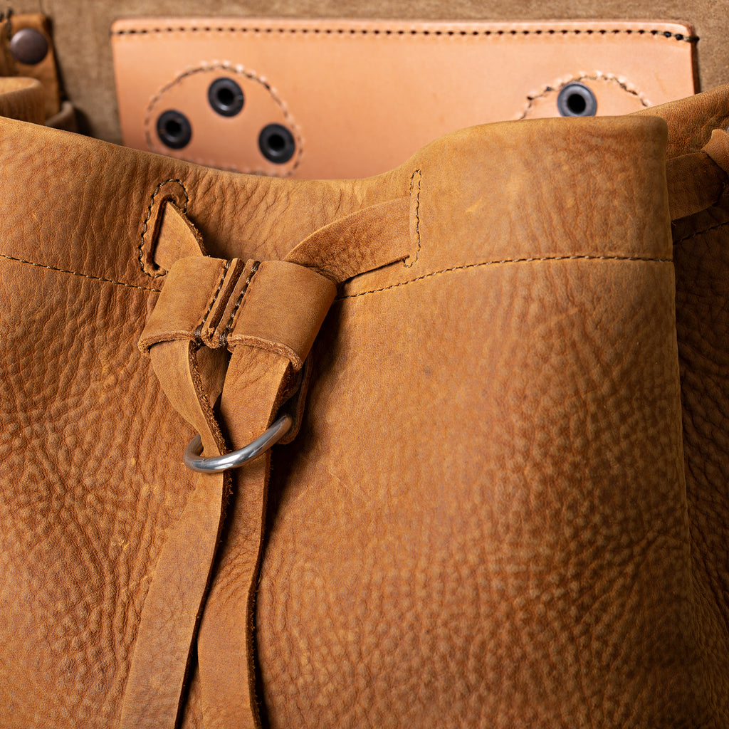 12" Drawstring Backpack in Tobacco, close-up of drawstring tie and ring below the open flap