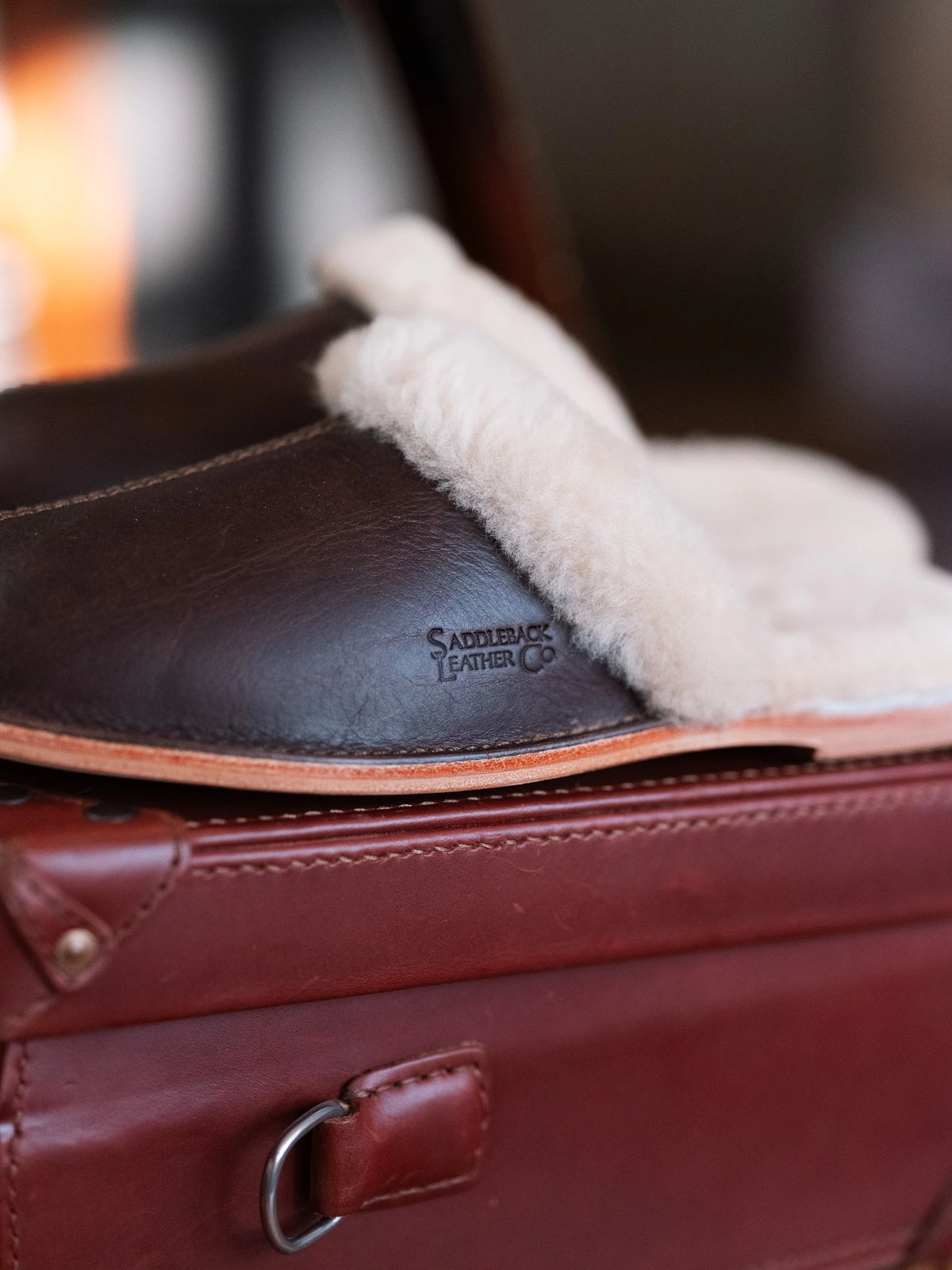 Sheepskin Slippers - Men - New Design in Dark Coffee Brown, close-up of the debossed logo and sheepskin trim on a leather bag