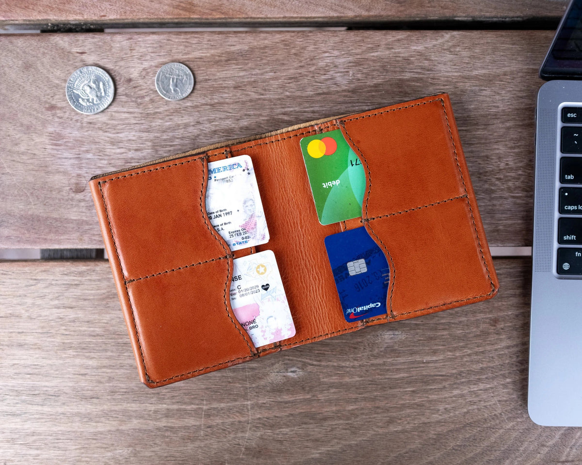 Large Bifold Wallet-Silverback in English Tan, top view open with cards in four slots beside coins and a laptop