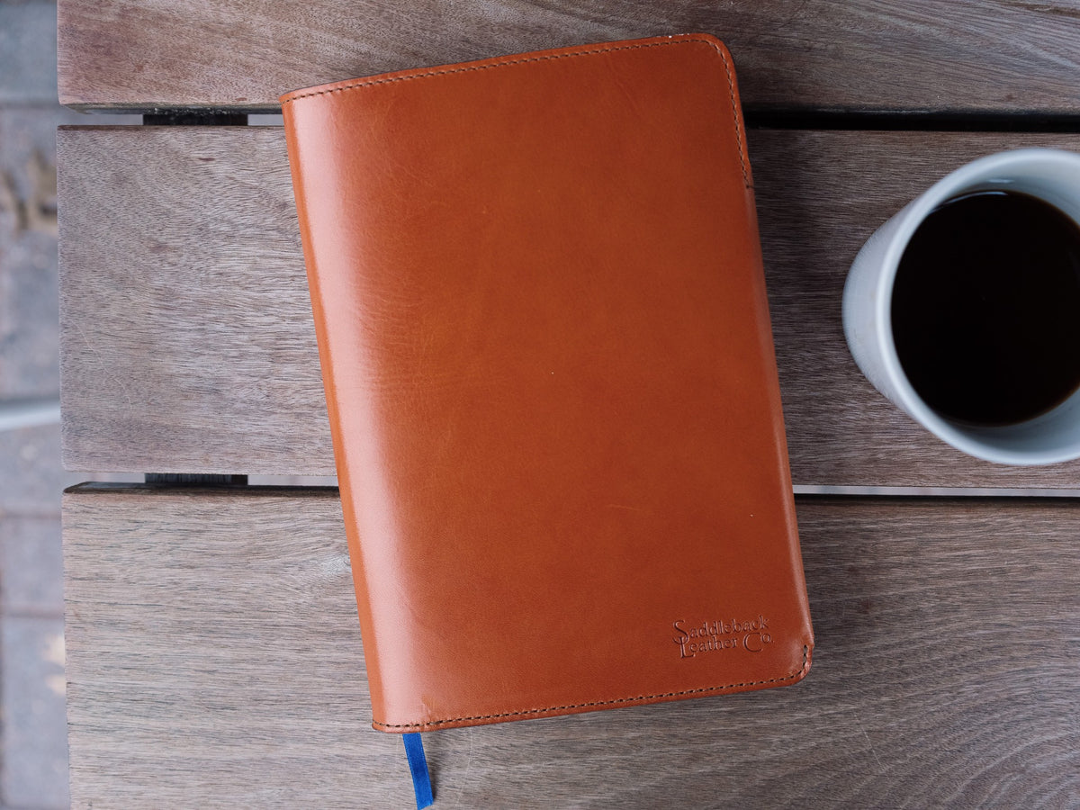 J.R.R. Tolkien Journal Cover in English Tan, closed front view with debossed logo beside a cup of coffee