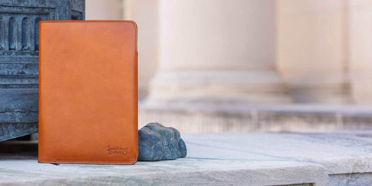 J.R.R. Tolkien Journal Cover in English Tan, closed and standing upright on marble steps beside a stone carving