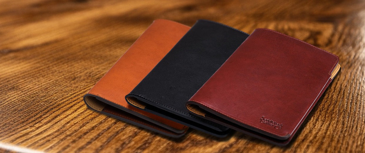 J.R.R. Tolkien Journal Cover in English Tan, Raven Black and Oxblood, three closed covers fanned on a wood table