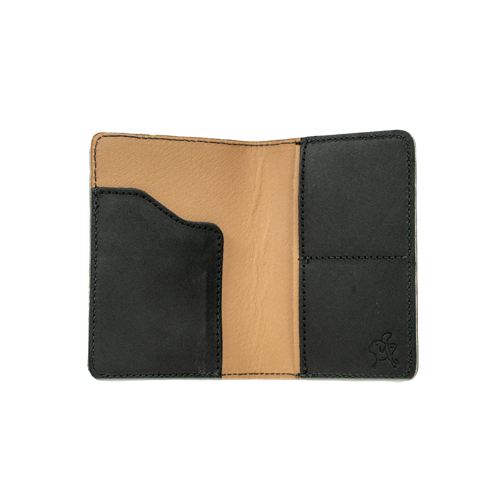 Slim Passport Wallet in Black opened flat to show the passport sleeve, card pockets and tan interior