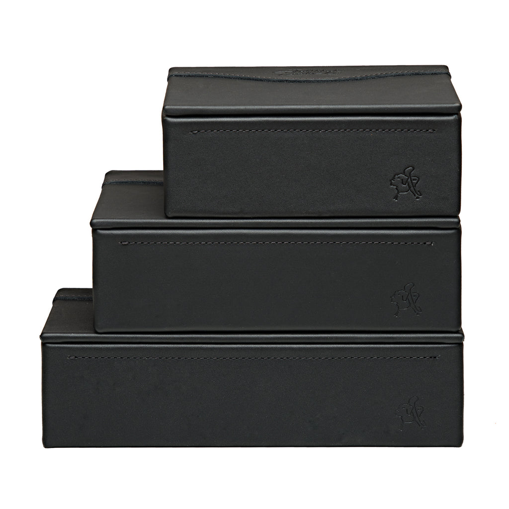 Small Organizer Box in Black stacked on two larger black leather boxes, each with embossed logo