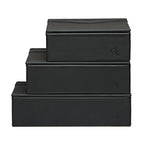 Small Organizer Box in Black stacked on two larger black leather boxes, each with embossed logo