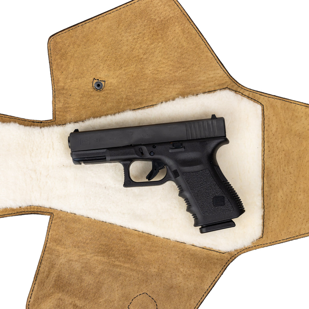 Leather Pistol Wrap in Tobacco laid open to show the fleece lining with a handgun resting inside