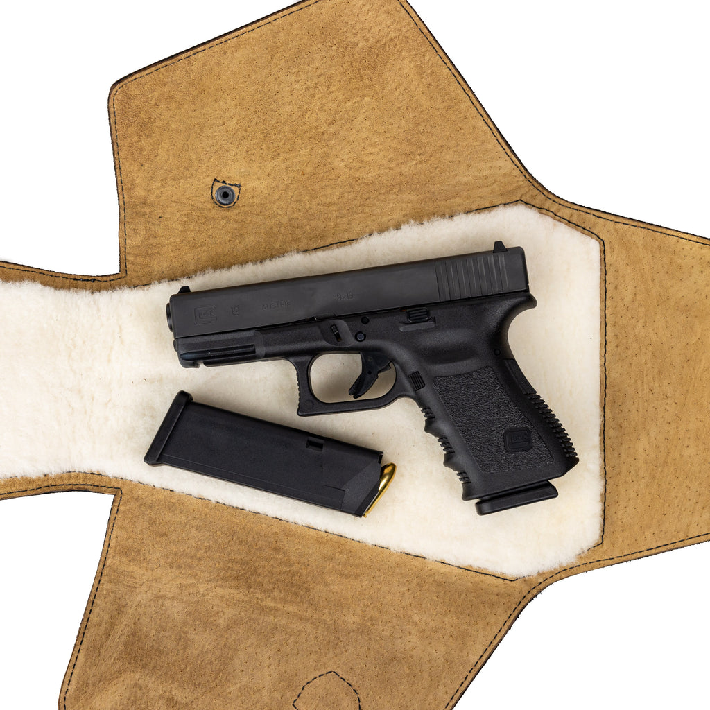 Leather Pistol Wrap in Tobacco laid open to show the fleece lining with a handgun and spare magazine