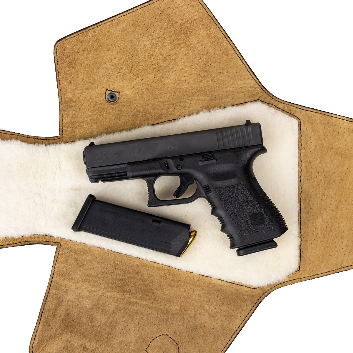 Leather Pistol Wrap in Tobacco laid open to show the fleece lining with a handgun and spare magazine