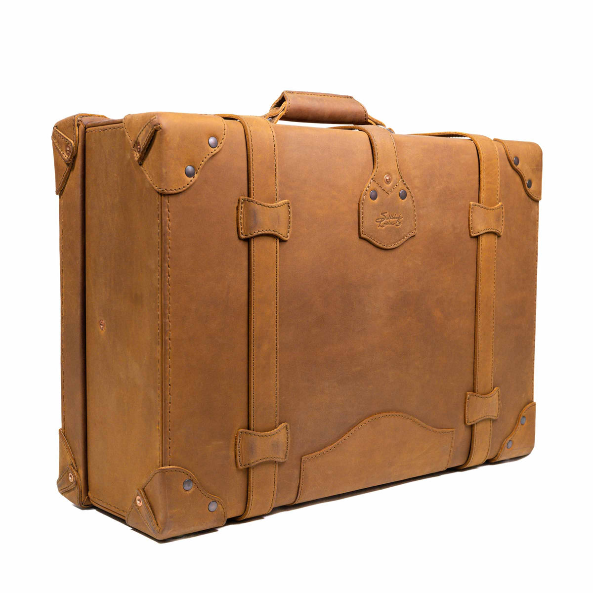 Grandfather Medium Suitcase in Tobacco, angled back view with top handle, straps and riveted corners