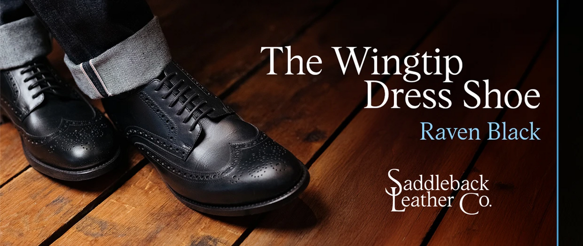 Wingtip Shoes - Raven Black worn with cuffed trousers on a wood floor, banner text The Wingtip Dress Shoe Raven Black